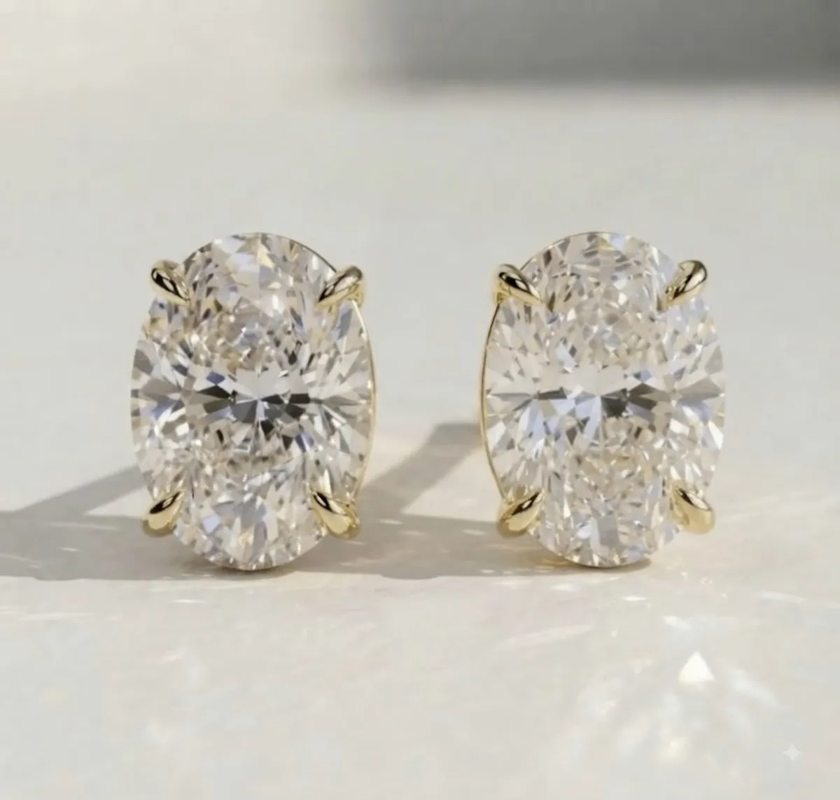 Oval diamond stud earrings in yellow gold — close-up detail