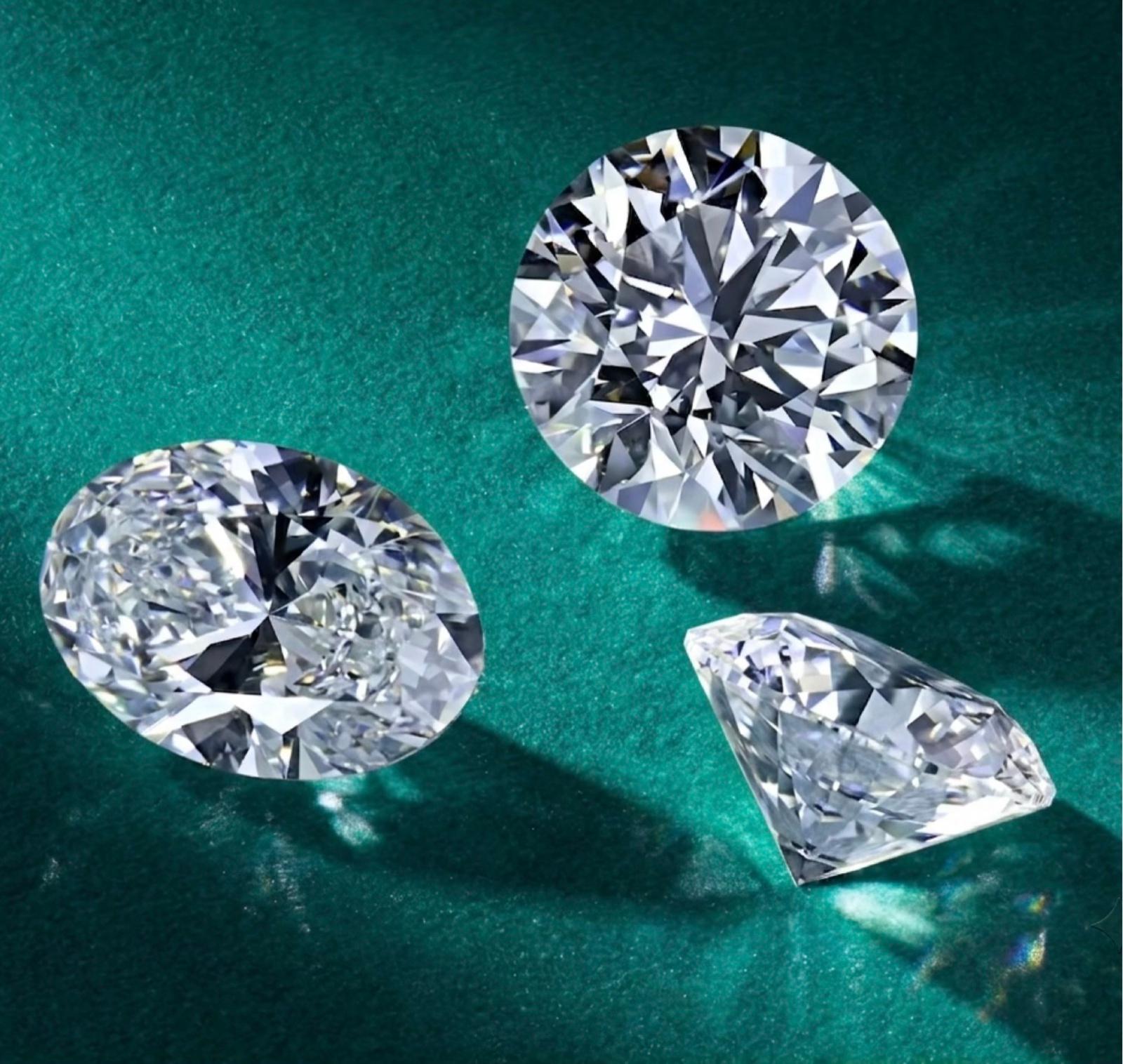 Three loose certified diamonds — round, oval and pear — displayed on a teal surface