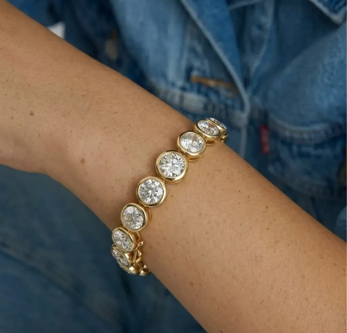Bezel-set diamond bracelet worn on wrist with denim