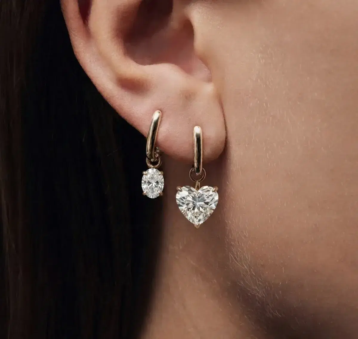 Heart and oval drop huggie earrings worn on ear