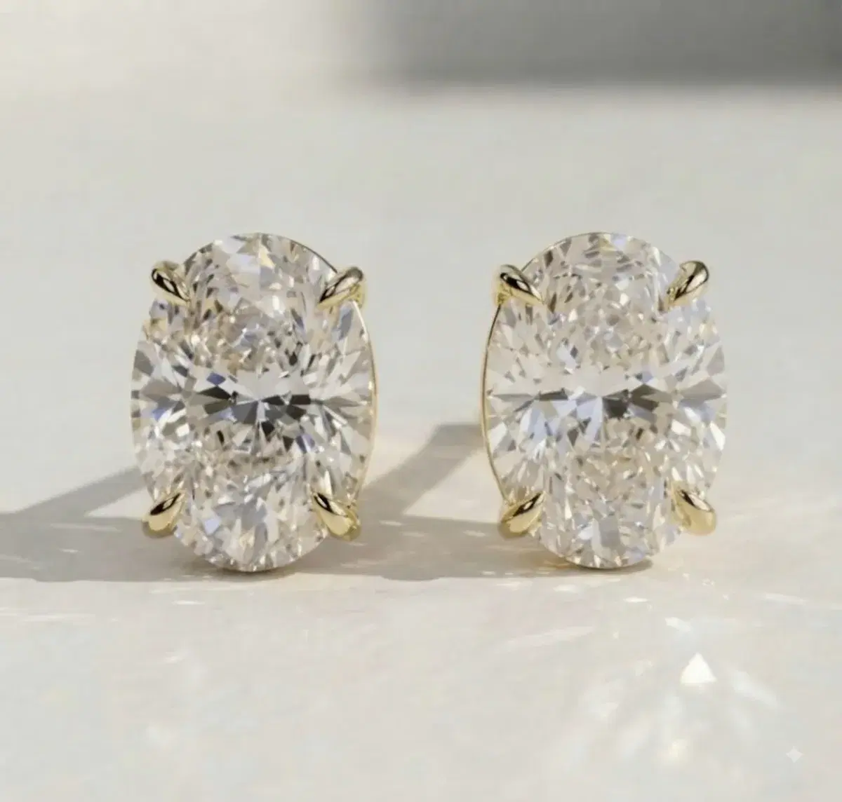 Oval diamond stud earrings in yellow gold — close-up detail
